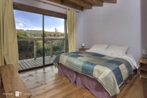 a bedroom with a bed and a large window at Antuquelen Lodge Cabañas in Frutillar