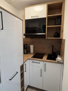 eine Küche mit weißen Schränken und einer schwarzen Mikrowelle in der Unterkunft Schmidt-einander in Norderney