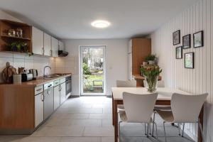 a kitchen with a dining table and white chairs at Hamburg - Haus - Airport 2 in Hamburg