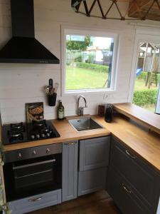 a kitchen with a sink and a stove and a window at Tiny House in Heerewaarden