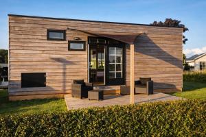 a tiny house sitting on a wooden deck at Tiny House in Heerewaarden