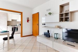a living room with a television and a table and a kitchen at Residenza Quadrifoglio in Cesena