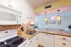 a kitchen with white cabinets and a sink at Comfortable 6th-floor beachfront condo with ocean views - walkable locale in Fort Walton Beach +31 photos