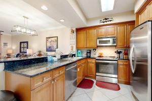 a kitchen with wooden cabinets and stainless steel appliances at First Floor Condo with a Partial Gulf View Splash Pad and More in Fort Walton Beach +20 photos