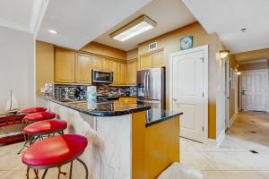 a kitchen with red stools at a counter with a refrigerator at Roomy beachfront condo with full kitchen shared pool and beach access in Fort Walton Beach +14 photos
