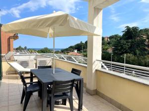 a black table and chairs with an umbrella on a balcony at Relax Ligure in Boissano
