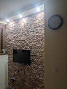 a tv on a brick wall with a clock at KRAGUJ apartments 1 in Kragujevac +2 photos