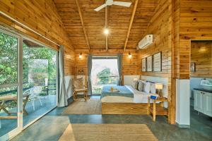 a bedroom with a bed and a large window at SaffronStays Anjee's Chalet in Dhamni