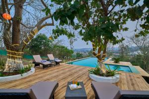 a wooden deck with chairs and trees and a swimming pool at SaffronStays Anjee's Chalet in Dhamni