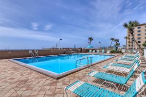 a swimming pool with blue lounge chairs in a resort at Spacious home with balconies shared pool and beach access in Fort Walton Beach