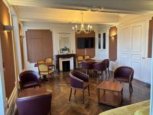 a dining room with tables and chairs and a fireplace at Château du Bourg in Saint-Denis-de-Gastines