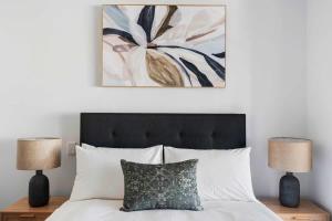 a bedroom with a bed with two lamps and a painting at Walk Everywhere - Large Apartment & Sofa Bed in Perth +26 photos