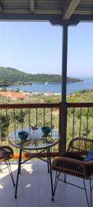 a table on a balcony with a view of the water at Skalopati Studios & Villa in Panormos Skopelos