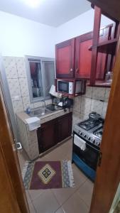 a kitchen with a stove and a sink and red cabinets at Home Soft in Douala +2 photos