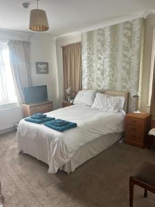 a bedroom with a large white bed with blue blankets at Brantwood Guest House in Christchurch