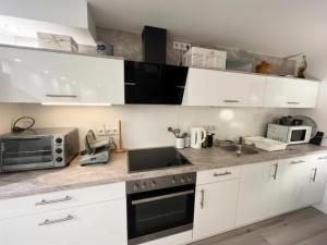 a kitchen with white cabinets and a sink and a microwave at Modernes Apartment nahe Frankfurt, Rodenbach & Hanau in Rodenbach +2 photos
