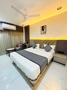 a bedroom with a large white bed and a table at Hotel M S Gold Ganadhinagar in Gandhinagar
