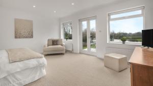 a bedroom with a bed and a chair and windows at The Nait in Fladbury