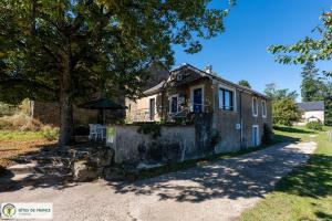 an old house with a table and an umbrella at "Gîte de Bel Horizon" in Broquiès