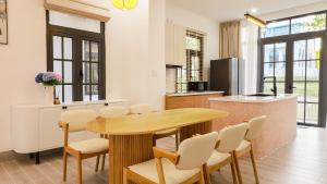 a kitchen and dining room with a wooden table and chairs at Bơ Home Novaworld in Phan Thiet