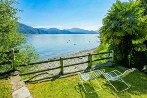 two chairs sitting on the grass near a body of water at Casa La Terrazza Uno C in Cannobio