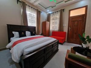 a bedroom with a large bed and a red chair at Mamucha Grand Lodge in Arusha +65 photos