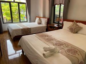 a hotel room with two beds and two windows at Son Tinh Hotel in Phong Nha