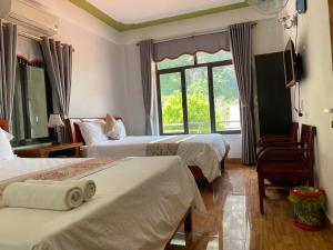 a hotel room with two beds and a window at Son Tinh Hotel in Phong Nha