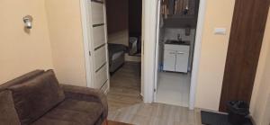 a living room with a couch and a hallway with a kitchen at Apartmani u srcu grada in Zrenjanin