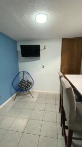 a room with a blue chair and a tv on a wall at Casa pequeña in Acapulco