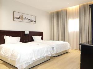 a bedroom with two beds with white sheets and a window at قصر الرحابة للشقق المخدومة in Hawāyā +13 photos