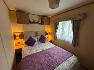 a bedroom with a bed with purple pillows and a window at The Cosy Hedgerow in Port Carlisle +67 photos