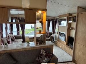 a living room with a couch and a tv at The Cosy Hedgerow in Port Carlisle