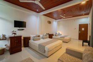 a bedroom with two beds and a flat screen tv at Ramboda Falls PLC in Ramboda