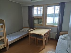 a small room with a table and a bed and a window at RIEKKO Hostel in Kuusamo