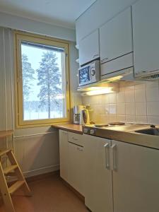 a kitchen with white cabinets and a window at RIEKKO Hostel in Kuusamo