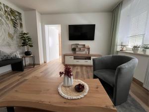 a living room with a table and a chair and a television at Ferienwohnung Hagert - Ankommen und Wohlfühlen in Eibenstock