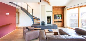 a living room with a couch and a staircase at Dorfhaus Chalets in Oberstaufen