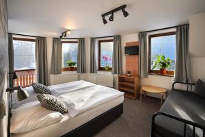 a bedroom with a bed and a desk and windows at Penzion Praděd in Malá Morávka +44 photos