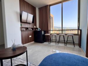 a living room with a table and chairs and a large window at Batroun Staycation in Batroûn