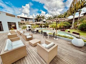 a patio with couches and tables and a pool at Be Cosy Private Villa - Trou aux Biches in Triolet