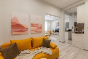 a living room with a yellow couch and a kitchen at NDK - UrbanLux Medius 2BDR FREE Parking in Sofia