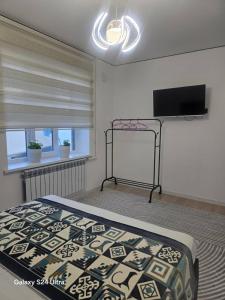 a bedroom with a bed and a flat screen tv at NovaMotel in Karakol