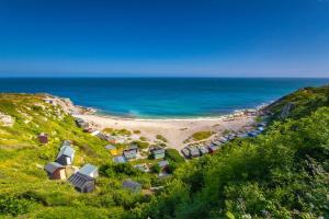 a beach with a group of huts and the ocean at Kivel Cottage in Portland