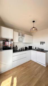 a kitchen with white cabinets and black counter tops at AMAO-Sepia - Spacious Family Apartment - 6 Guests - Parking in Rheinhausen