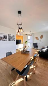a dining room and living room with a wooden table and chairs at AMAO-Sepia - Spacious Family Apartment - 6 Guests - Parking in Rheinhausen