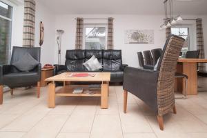 a living room with a black leather couch and a table at Ferienhaus Carpe Diem in Greetsiel +17 photos