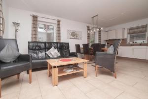 a living room with black leather furniture and a table at Ferienhaus Carpe Diem in Greetsiel
