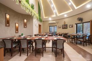 a restaurant with wooden tables and chairs and windows at Treebo Premium Mowgli's Den, Pench Tiger Reserve, Turia in Khawāsa