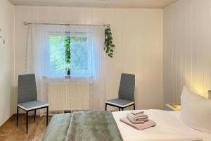 a bedroom with two chairs and a bed and a window at Gartenblick in Lübbenau